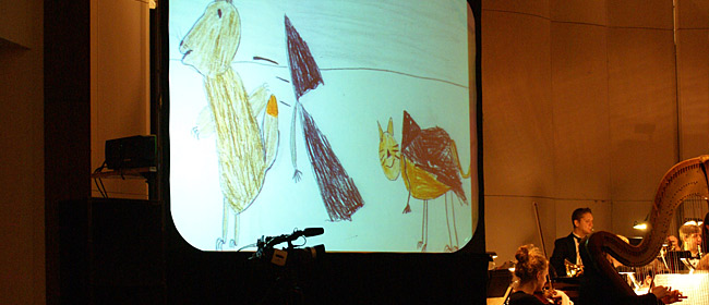 Student illustrations are projected on a large screen
